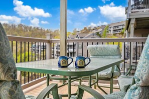 A balcony with two blue mugs on a glass table, surrounded by green chairs and a railing. - Beautiful Lake View Condo, Newly Updated & Ideally Located (Branson)