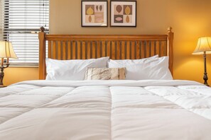 A neatly made bed with white linens, a wooden headboard, and two framed artworks on the wall above. - Beautiful Lake View Condo, Newly Updated & Ideally Located (Branson)