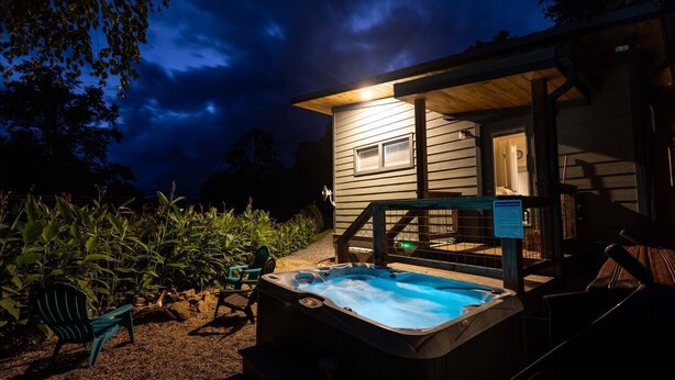 A cozy cabin with a hot tub, wooden deck, and a small porch. - Time Flies on the River (Bryson City)