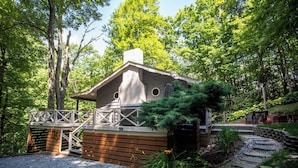 A cabin with a wooden deck, a covered porch, and a stone pathway leading to a bench area. - Charming Mountain Cabin Near Boone (Boone)