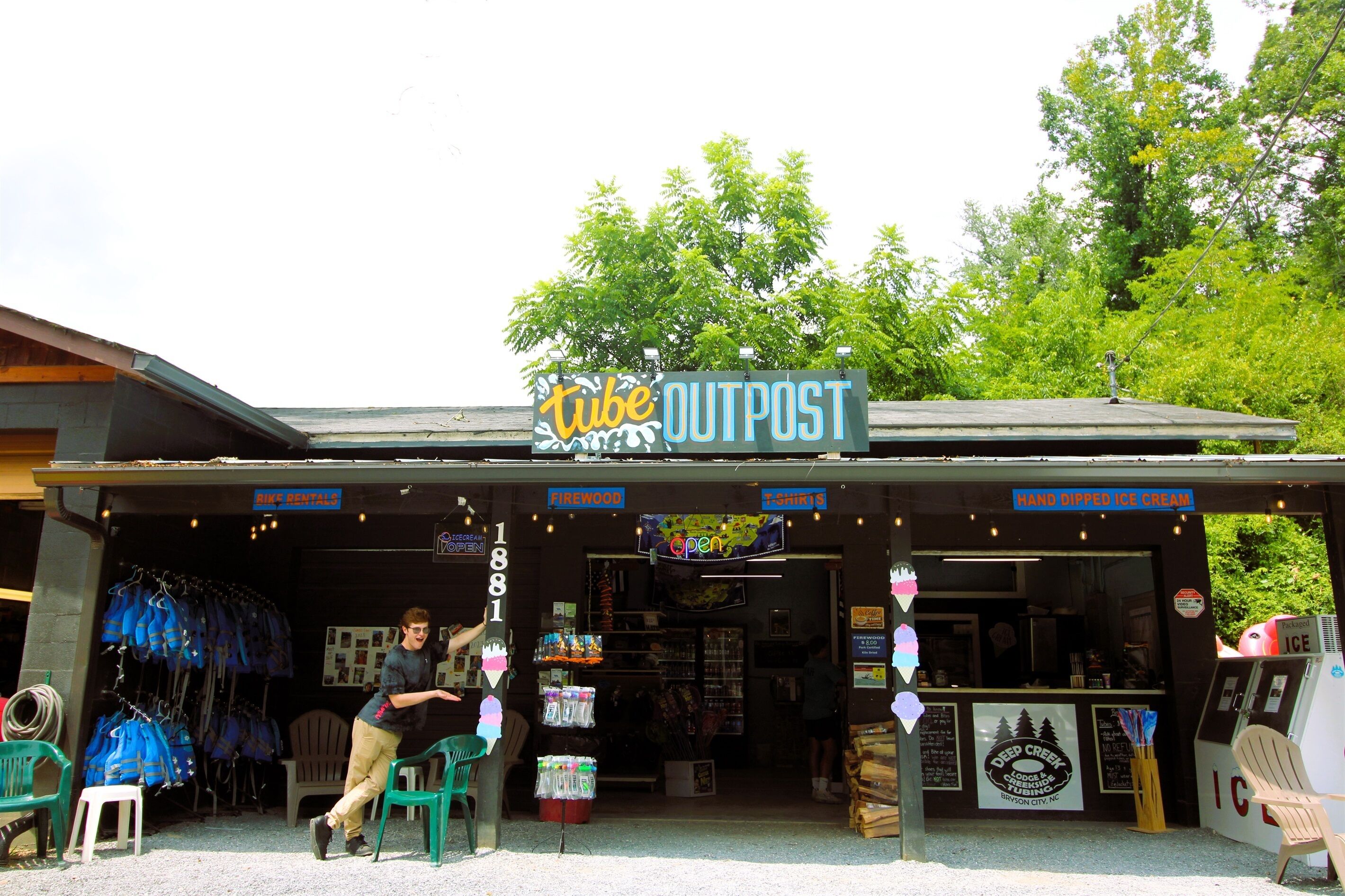 Ein Geschäft mit einem Schild, auf dem "Tube OUTPOST" steht, und verschiedenen Waren, darunter Brennholz und T-Shirts.