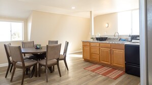 Una cocina moderna con armarios de madera, encimera de granito y zona de comedor con mesa y sillas.