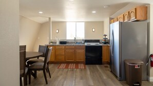 Una cocina con armarios de madera, un refrigerador de acero inoxidable, una estufa y una mesa de comedor con sillas.