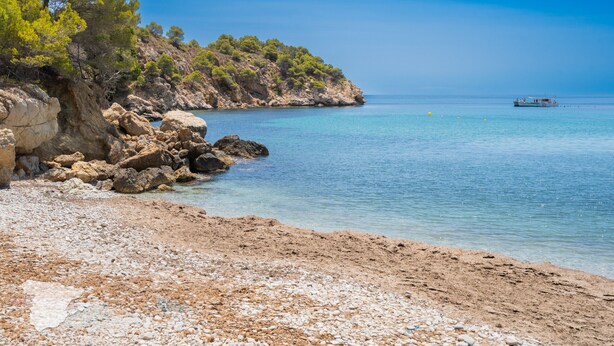 A rocky beach with clear blue water and a boat in the distance. - CostaBlancaDreams - Dinamarca in Altea Hills (Altea)