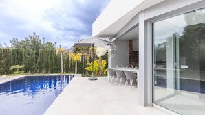 A modern outdoor pool area with a dining setup and a glass-enclosed space. - CostaBlancaDreams - Villa Gran Sol en Calpe (Calpe)