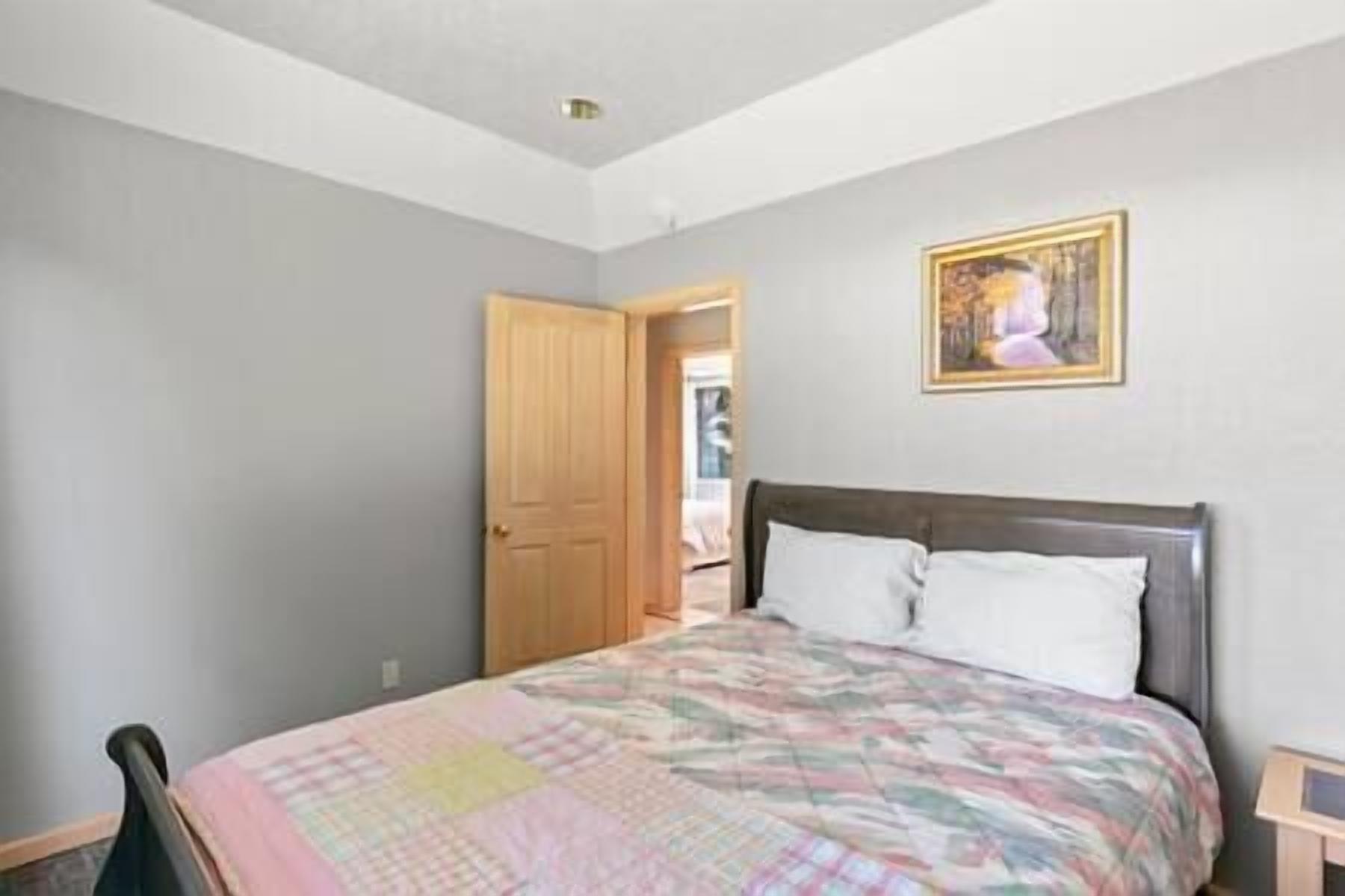 Une chambre à coucher avec un lit, une porte et un tableau au mur.