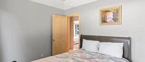 Une chambre à coucher avec un lit, une porte et un tableau au mur.