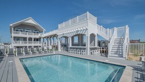 A large, two-story building with a swimming pool, outdoor seating, and a covered patio area. - 5373 - Wench's Pad 4 - Luxury Oceanfront Retreat | Sleeps 40 (Kill Devil Hills)