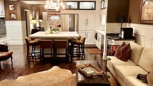 A modern kitchen with a central island, bar stools, and pendant lighting. - Enjoy a Poolside Luxury Condo and dock, & only a 3 min walk to Vanderbilt Beach. (Naples)