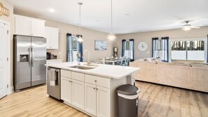 A modern kitchen with a central island, stainless steel appliances, and pendant lighting.