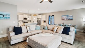 A spacious living room with a sectional sofa, a dining area, and a kitchen.