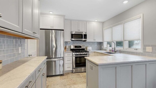 Una cocina moderna con electrodomésticos de acero inoxidable, armarios blancos y una isla grande.