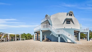 Een uniek, meerlaags strandhuis met een opvallende trap en een balkon.