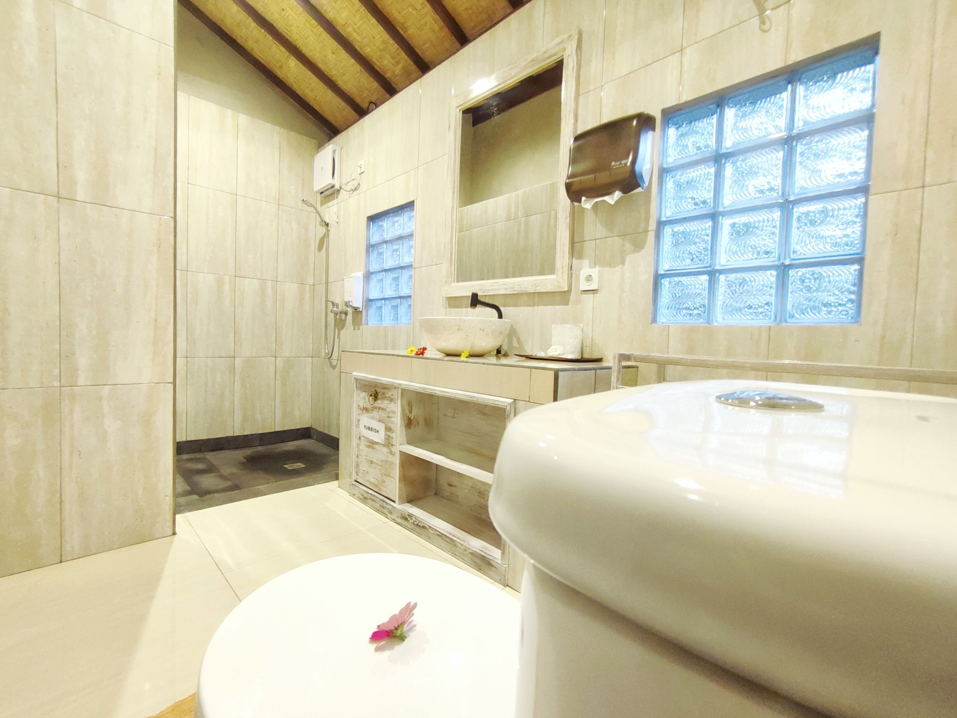 A bathroom with a white sink, a mirror, and a window with frosted glass.