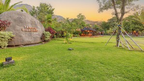 A large rock with "TAMAN BIDADARI" inscribed, a grassy area with a wooden structure, and a tree. - Taman Bidadari Eco & Wellness (Pemuteran)