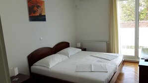 A bedroom with a bed, a radiator, a window, and a painting on the wall. - Baletna Skola (Kastela)