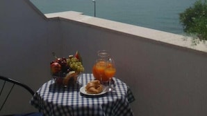 A table with fruit and juice on a balcony overlooking a body of water. - Baletna Skola (Kastela)