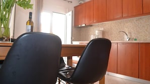 A modern kitchen with wooden cabinets, a dining table with chairs, and a potted plant. - Lovely 3-Bed House in Bali (Bali)