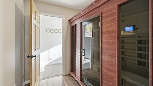 A hallway with a wooden door, a glass door with a handle, and a television on a shelf. - Large Family Retreat Pool Hot Tub Game Room Sauna (Lake Havasu City)