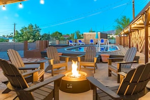 Une terrasse extérieure avec un foyer, des fauteuils et un espace piscine.