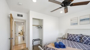 A bedroom with a bed, a ceiling fan, a bedside table, a nightstand, a hanging chair, a wardrobe, and a door leading to another room. - Large Family Retreat Pool Hot Tub Game Room Sauna (Lake Havasu City)