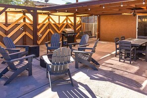 Une terrasse extérieure avec des fauteuils Adirondack, un barbecue et une table.