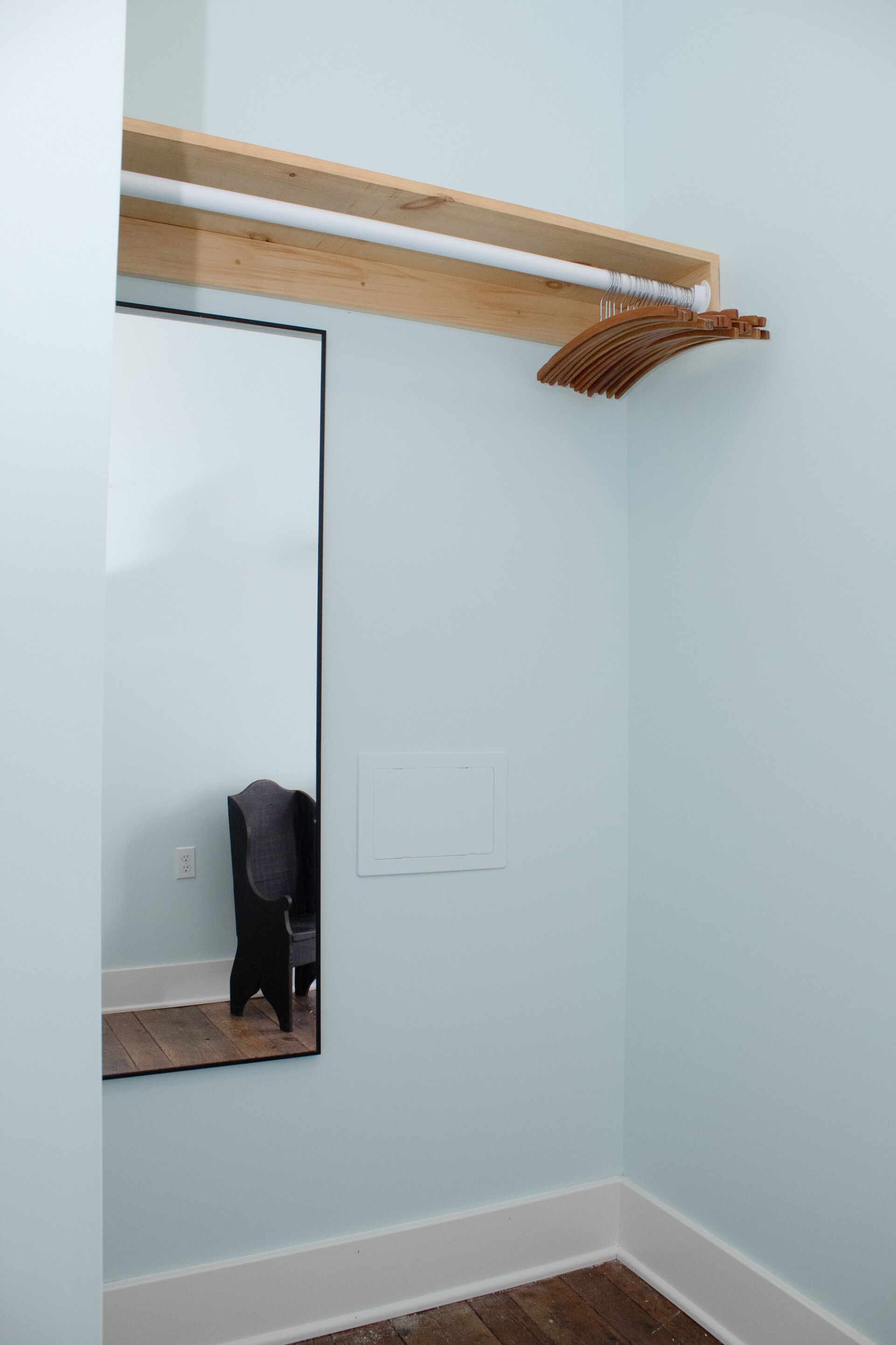 A room with a large mirror, a wooden beam above the mirror, and a light switch on the wall.