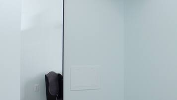 A room with a large mirror, a wooden beam above the mirror, and a light switch on the wall.