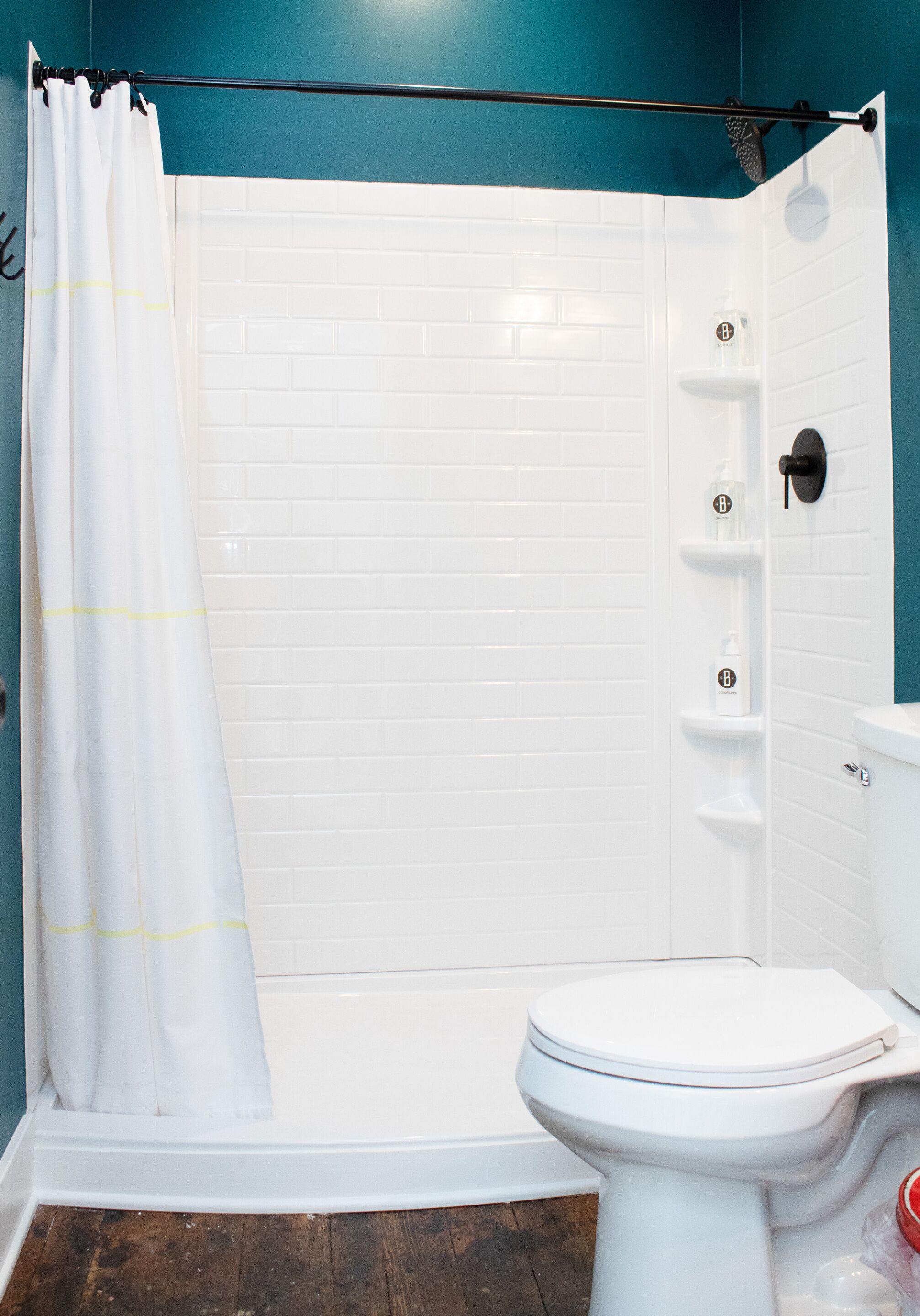 A bathroom with a white shower enclosure, a white toilet, and a blue wall.