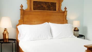 Una cama de madera con ropa de cama blanca, dos mesitas de noche con lámparas y un cabecero de madera.