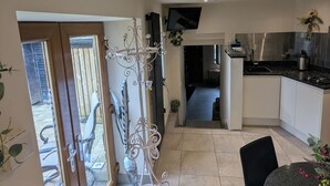 Una cucina moderna con zona pranzo, TV a parete e una porta scorrevole in vetro che dà su un patio esterno.