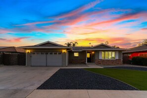 A residential house with a garage, a driveway, and a well-maintained lawn. - Luxury Oasis, Hot Tub, Outdoor Kitchen and Grill, Arcade Room, Sleep up to 13 (Fresno)