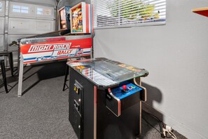 A room with a table tennis table and a pinball machine.