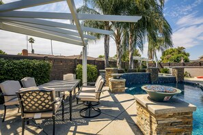 An outdoor patio with a pool, stone walls, and a pergola.