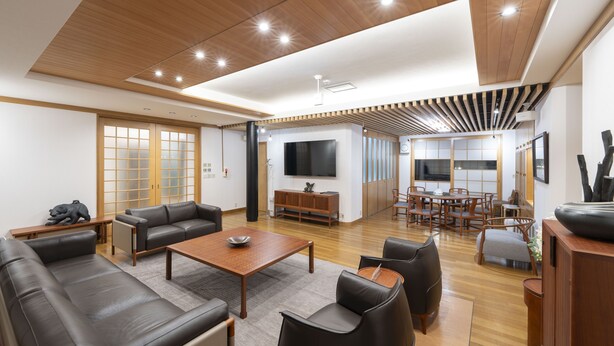 Un salón espacioso con techo de madera, un televisor de pantalla plana grande y un comedor con mobiliario de madera.