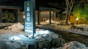 Un cartel de hotel con una entrada cubierta de nieve y un edificio moderno al fondo.
