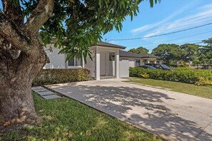 A residential property with a paved driveway, a garage, and a well-maintained lawn. - Close To Airport, Miami & Wynwood New Modern Home! (Miami)