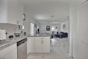 A modern kitchen with white cabinetry, a marble countertop, and a dishwasher. - Close To Airport, Miami & Wynwood New Modern Home! (Miami)