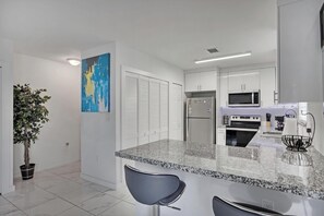 A modern kitchen with white cabinetry, a granite countertop, and stainless steel appliances. - Close To Airport, Miami & Wynwood New Modern Home! (Miami)