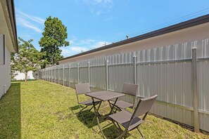 A fenced backyard with a grassy lawn and a table with chairs. - Close To Airport, Miami & Wynwood New Modern Home! (Miami)