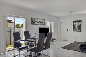 Un espace repas moderne avec une table en verre, des chaises noires et un téléviseur à écran plat.