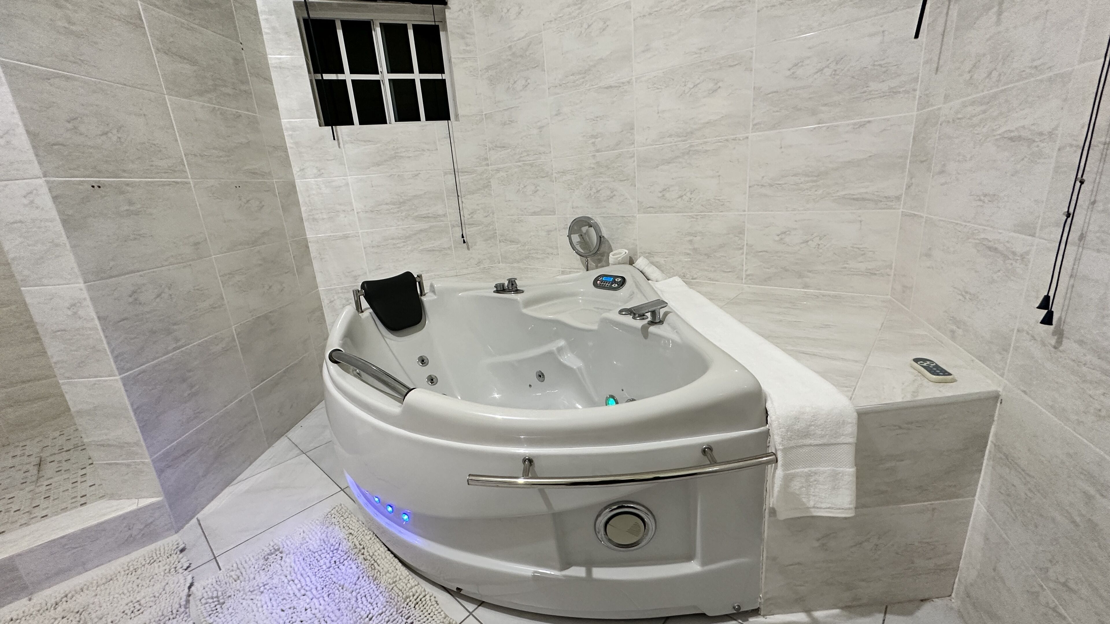 Een moderne badkamer met een vrijstaand bad, een handdouche en een handdoekhouder.