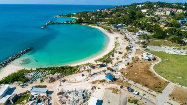An aerial view of a coastal area with a beach, a pier, and residential buildings. - Villa Nilaja (Montego Bay)