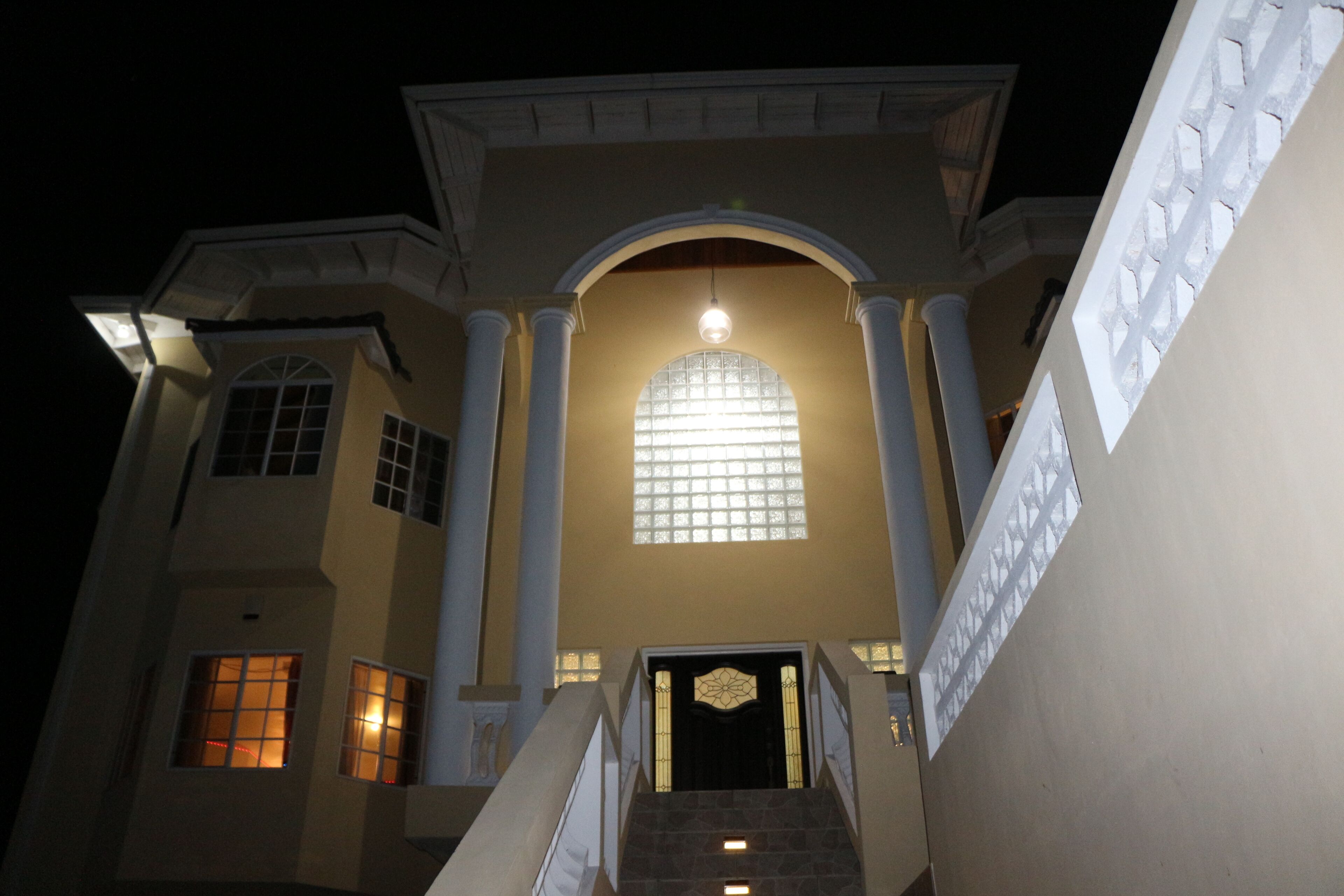 A grand entrance with a large arched window and a staircase leading up to a door with a decorative glass panel.