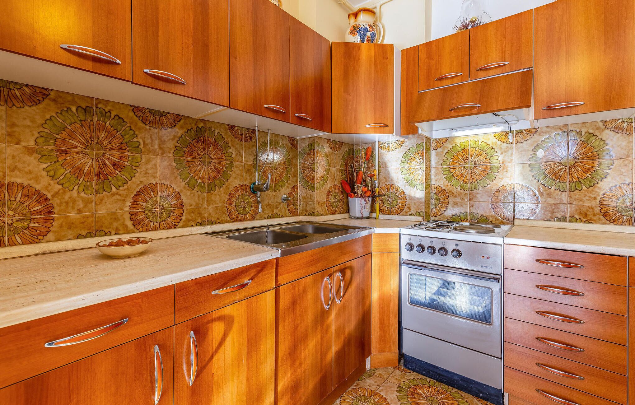 A kitchen with wooden cabinets, a stainless steel sink, and a stove.