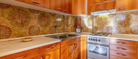 A kitchen with wooden cabinets, a stainless steel sink, and a stove.