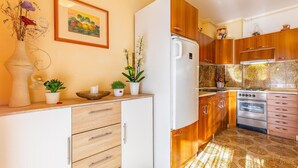 Cuina amb armaris de fusta, nevera blanca, forn i resclosa de rajola.