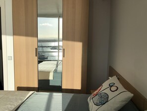 Un dormitorio con cama, vista de un puerto deportivo a través de una puerta corrediza y ventana con vista al agua.