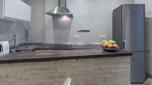 A modern kitchen with grey tiles, a stainless steel range hood, a built-in oven, and a refrigerator. - Julio Cesar Great Apartment Of High Qualities Heart Of Seville (Sevilla)