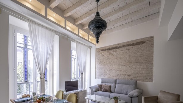 A modern living room with a grey sofa, a coffee table, and a dining area with a wooden table set for four. - Julio Cesar Great Apartment Of High Qualities Heart Of Seville (Sevilla)